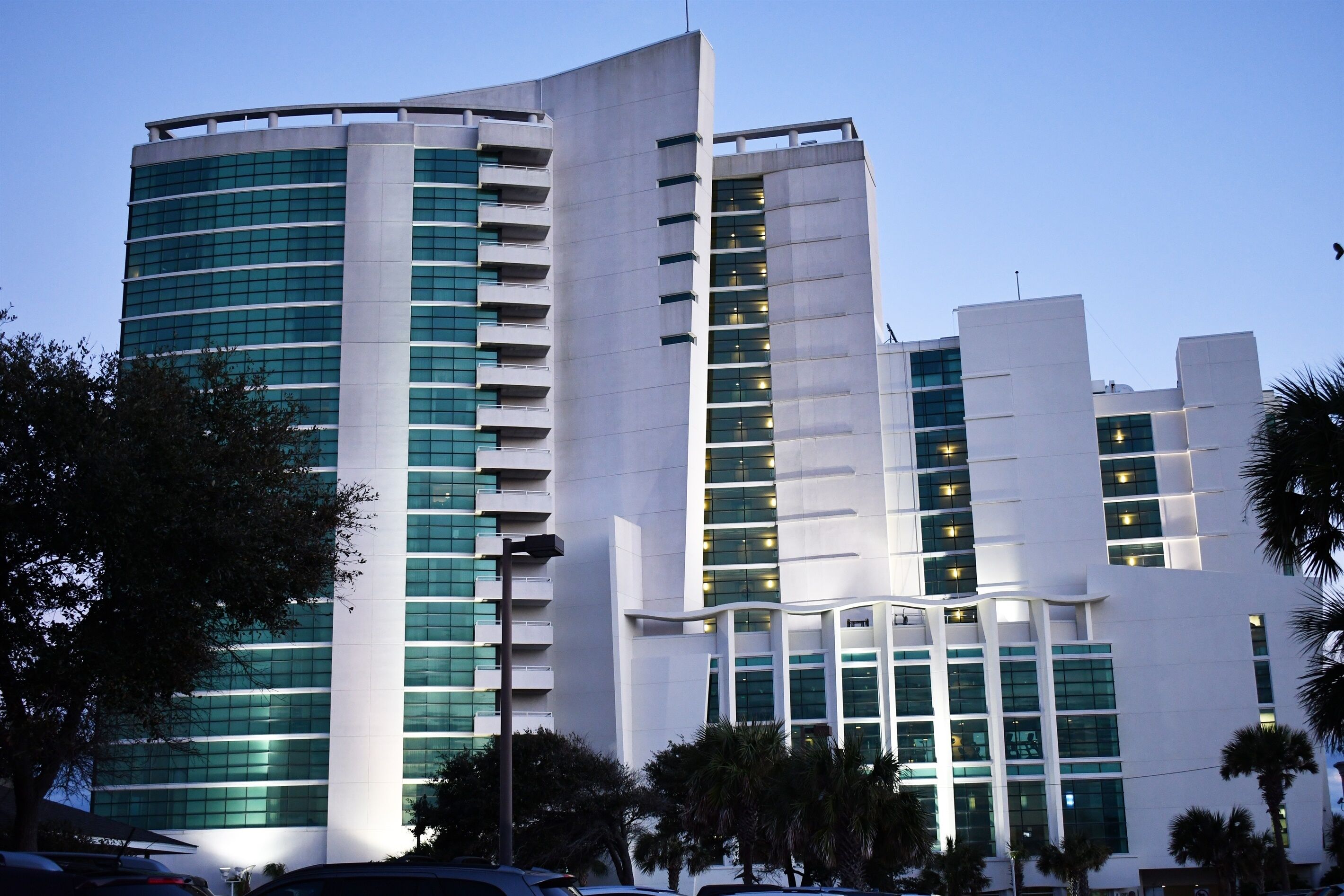 A modern multi-story building with a curved facade, large windows, and balconies.