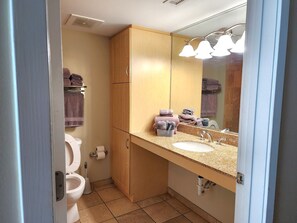 Un baño con inodoro, lavamanos, espejo y toallero.