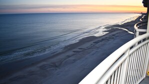 Ein Balkon mit Blick auf einen Strand bei Sonnenuntergang.