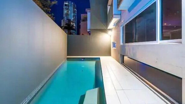 A modern indoor pool area with a clear view of the city skyline in the background. - Wow Large 4 Bedrooms 4 bathroom with Private pool, 4 min walk to beach (Surfers Paradise)
