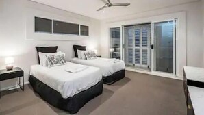 A bedroom with two beds, a ceiling fan, and a sliding glass door to the right. - Wow Large 4 Bedrooms 4 bathroom with Private pool, 4 min walk to beach (Surfers Paradise)