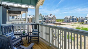 A covered outdoor area with a wooden deck, a table, and chairs. - Inviting beach-front townhouse with pool, balcony, water views, & W/D (Port Aransas)