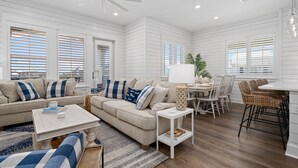 A spacious living room with a sofa, coffee table, and dining area. - Inviting beach-front townhouse with pool, balcony, water views, & W/D (Port Aransas)