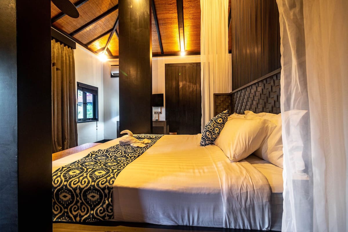 A room with a bed, a window, a television, and a door.