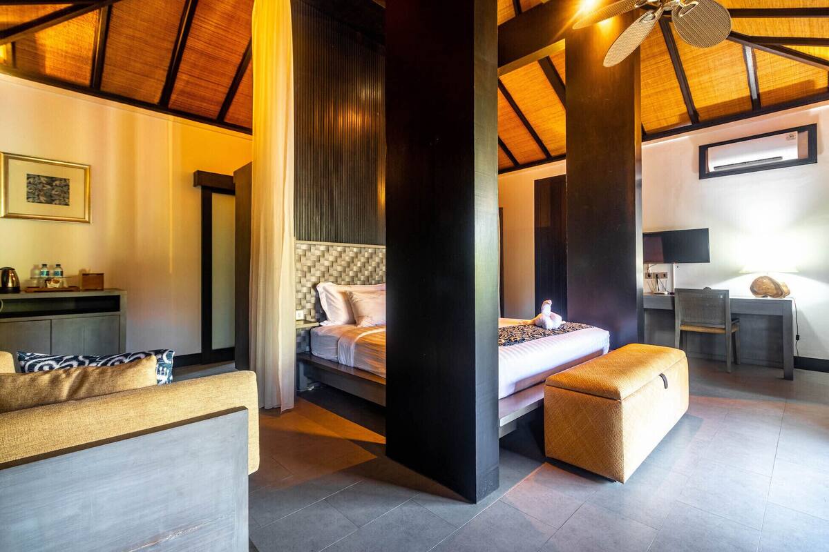 A modern hotel room with a large bed, a desk, a chair, and a television.