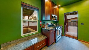 A kitchen with green walls, wooden cabinets, granite countertops, a stove, and a microwave.