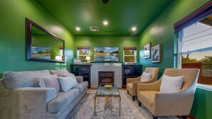 A living room with a fireplace, green walls, a sofa, armchairs, and a coffee table.