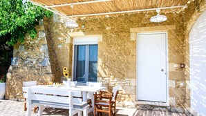 Un patio al aire libre con un muro de piedra, una mesa blanca y sillas.