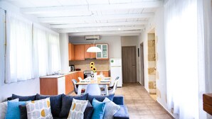 Una sala de estar moderna con un sofá, un comedor con mesa y sillas, y una cocina al fondo.