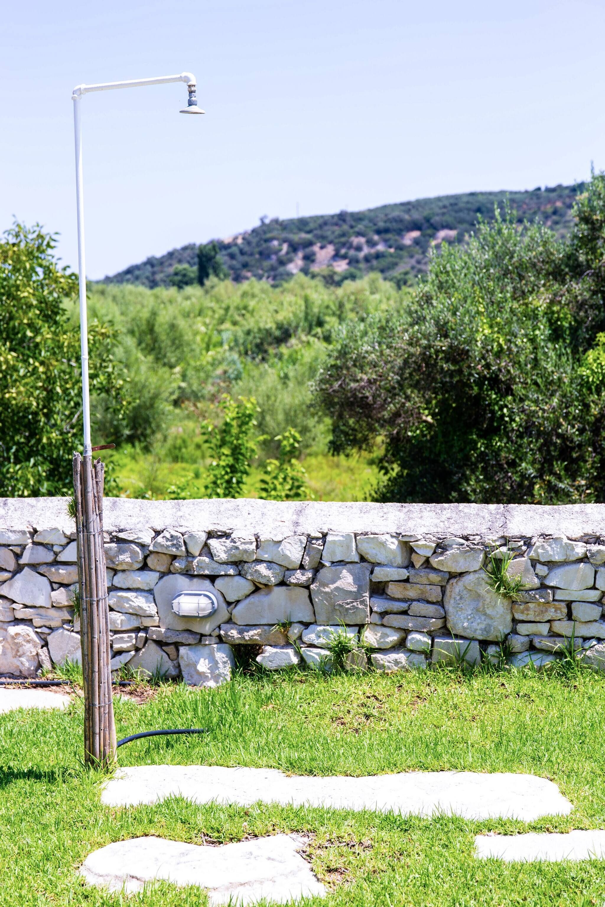 A stone wall with a metal lamp post in a grassy area with stone steps.