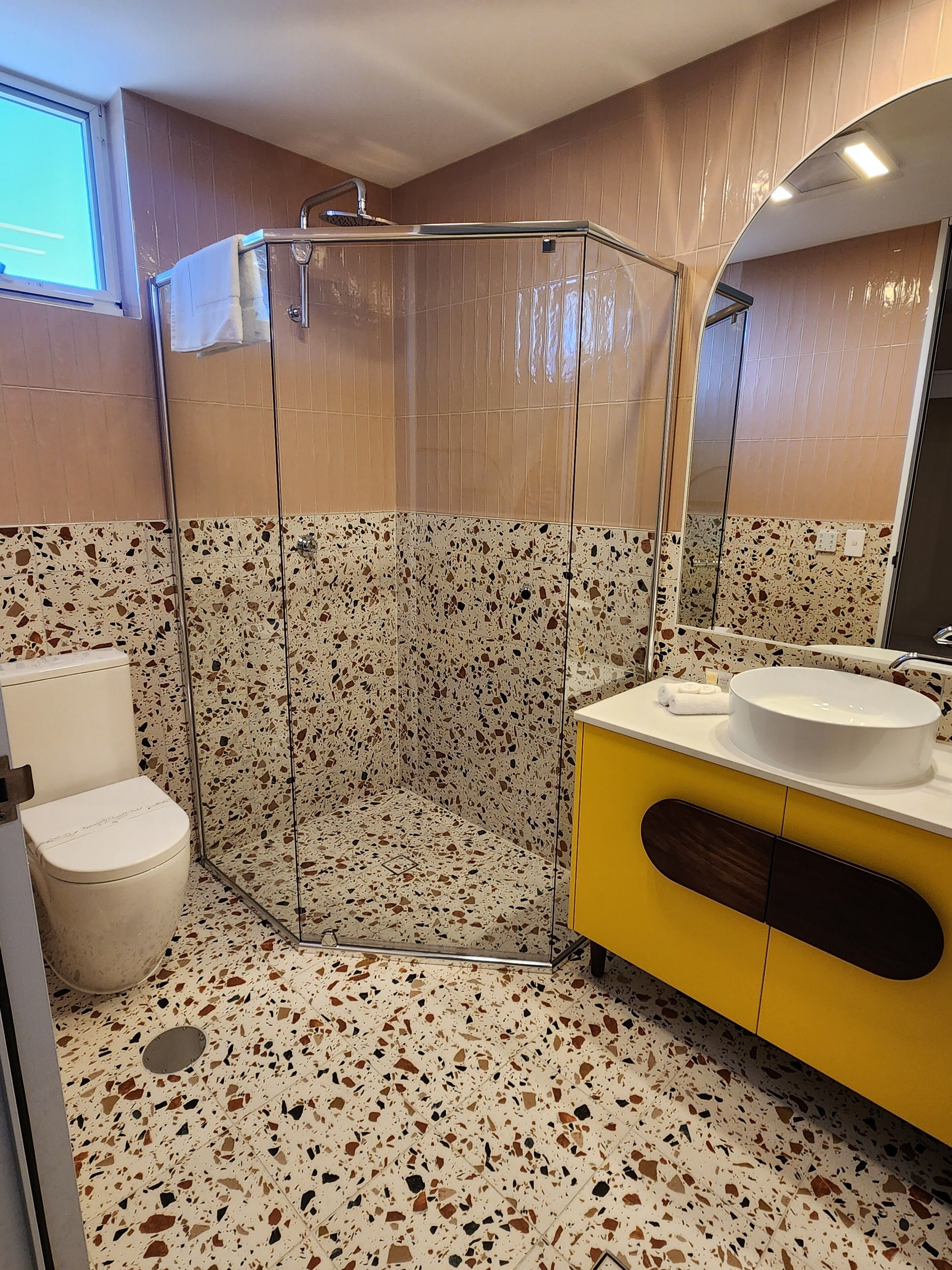 Een badkamer met een douchecabine, toilet en een wastafel met spiegel.