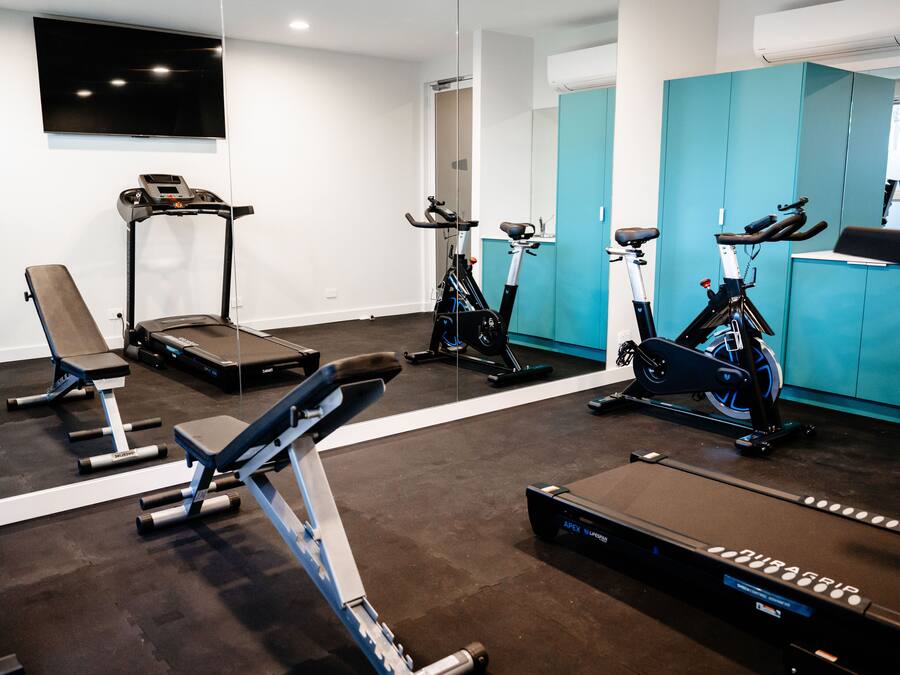 Una palestra con attrezzature per esercizi, tra cui tapis roulant, ellittica e panca.