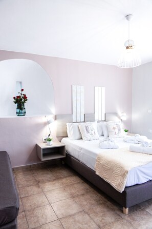 A modern bedroom with a bed, bedside tables, a vase with flowers, and a mirror.
