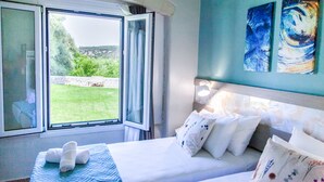 Une chambre à coucher avec un lit, des oreillers, une fenêtre et des œuvres d’art accrochées au mur.
