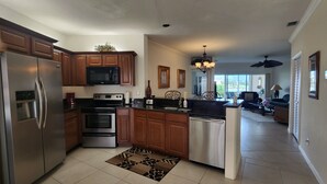 A modern kitchen with stainless steel appliances, wooden cabinets, and a central island.