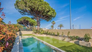 A swimming pool with a clear blue water, surrounded by well-maintained grass and a variety of plants.
