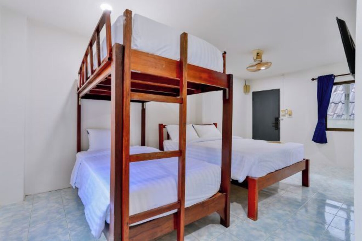 A bunk bed room with a wooden frame, white bedding, and a window with curtains.
