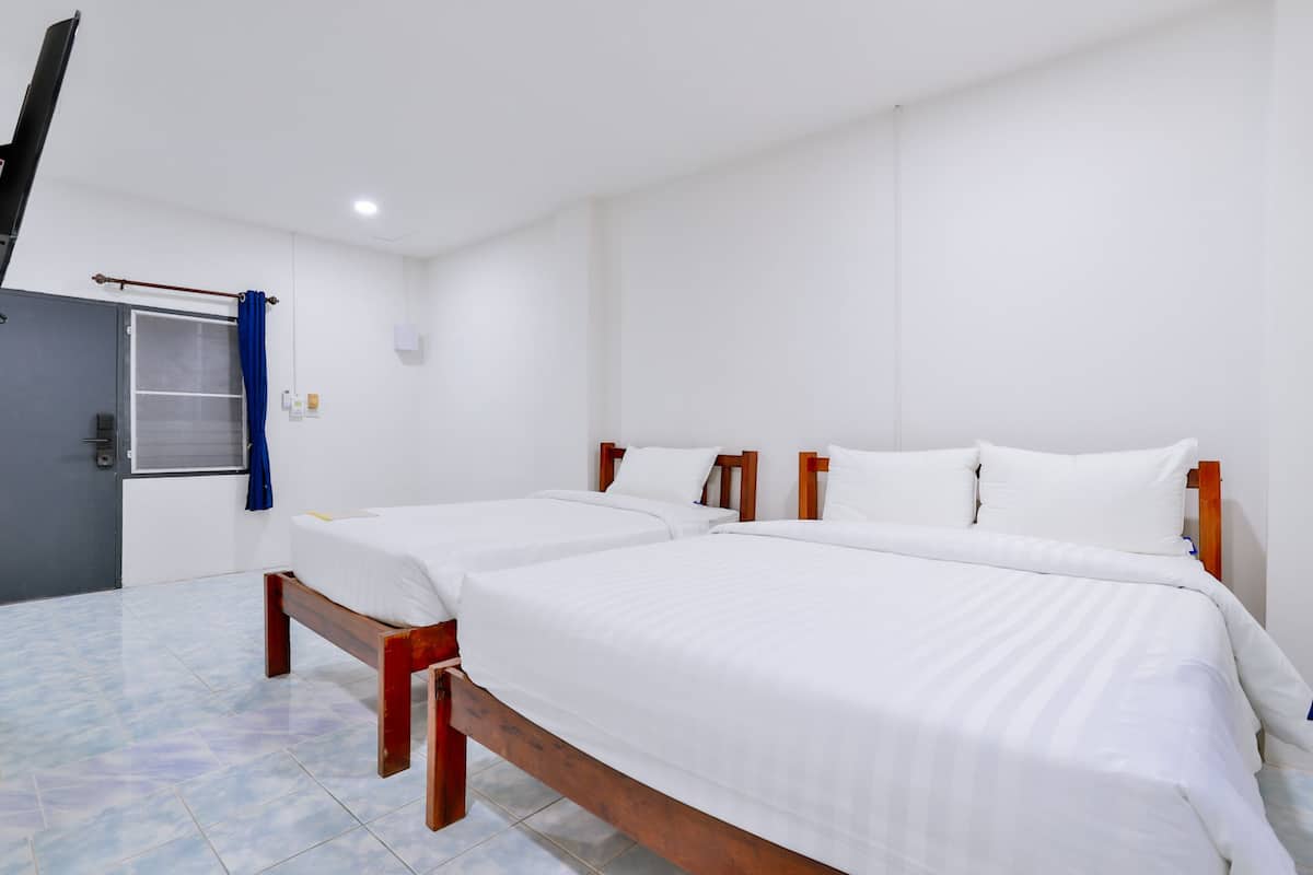 A hotel room with two beds, a wooden headboard, white bedding, a blue curtain, and a door with a handle.