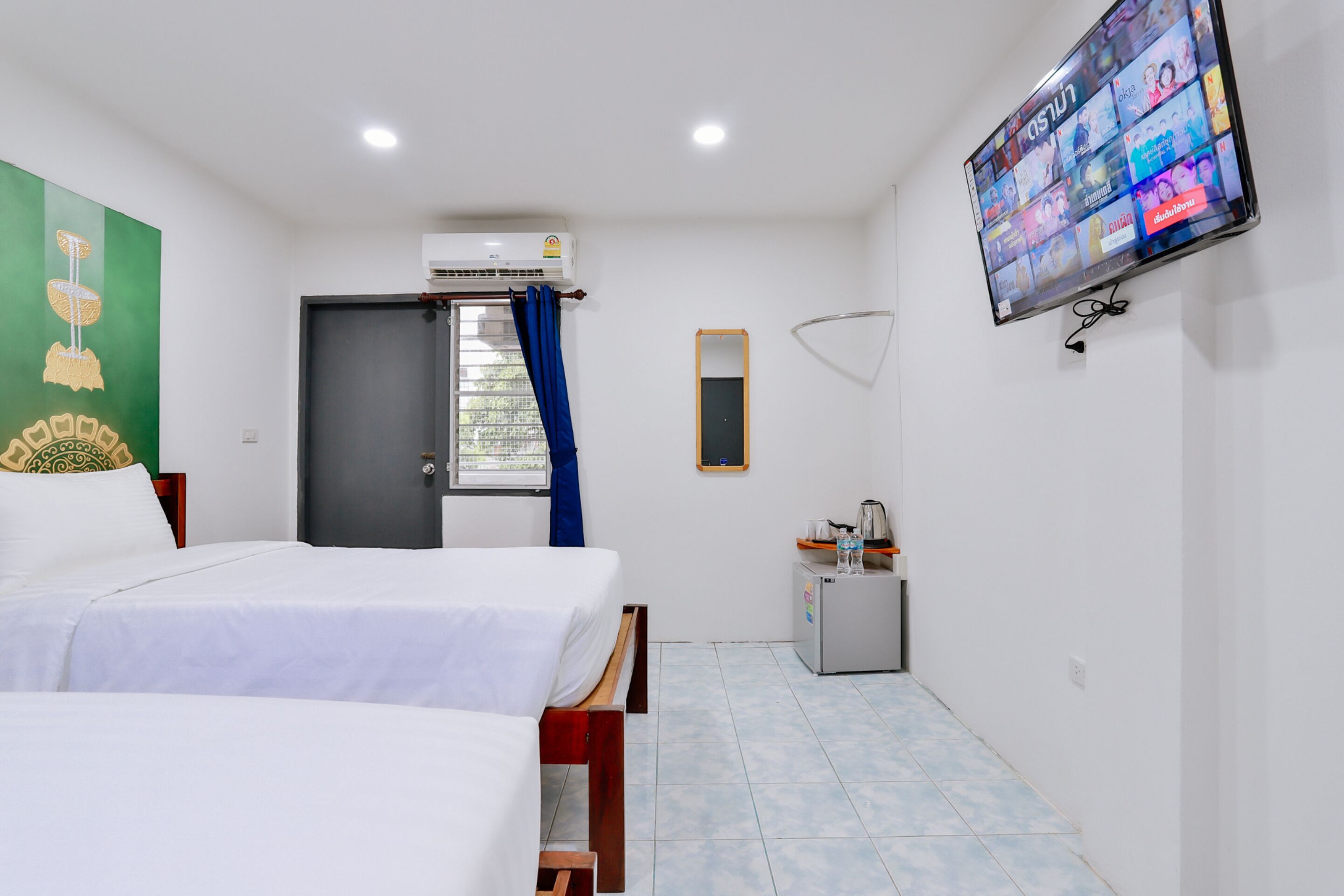 Une chambre d’hôtel avec deux lits, une télévision, une petite kitchenette et une fenêtre avec des rideaux.