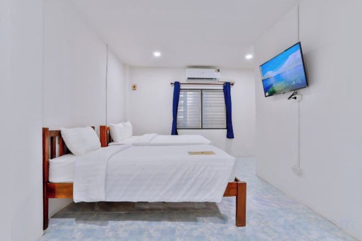 A bedroom with a bed, a television mounted on the wall, and an air conditioning unit.