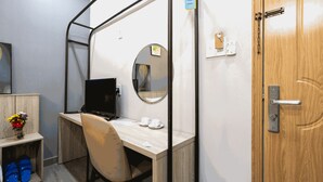 A small, private room with a wooden desk, a chair, a computer, a mirror, and a door with a handle. - THE COZY INN (Ho Chi Minh City)