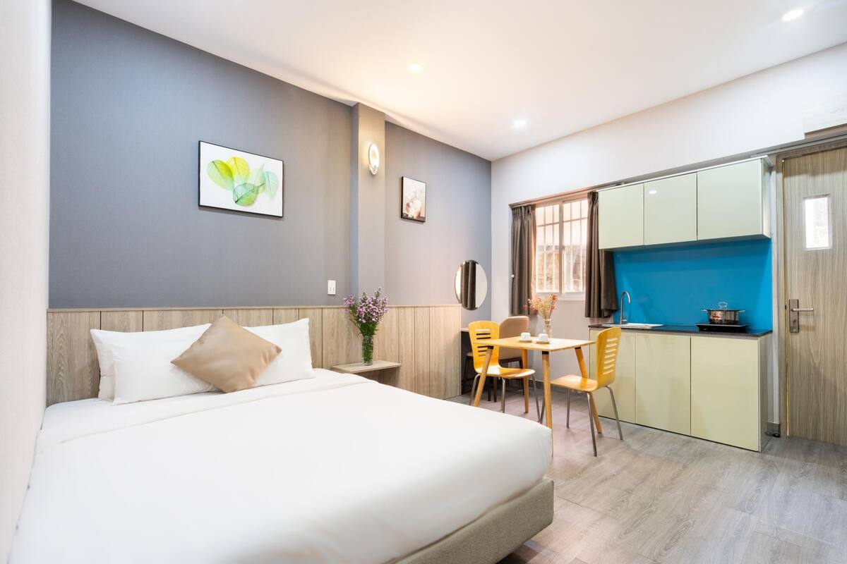 Een hotelkamer met een bed, een eettafel met stoelen, een kitchenette en een badkamer met douche.