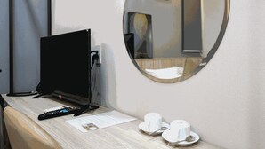 A hotel room with a desk, a television, a mirror, and two cups on the counter. - THE COZY INN (Ho Chi Minh City)