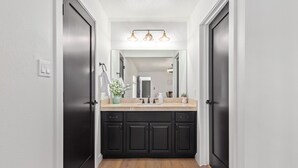 Un baño moderno con tocador de madera oscura, espejo y lámpara sobre el lavabo.