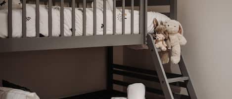 Un lit superposé avec une échelle, des oreillers et des peluches.