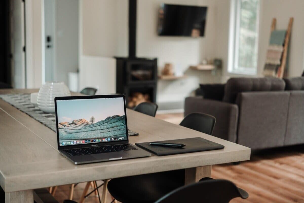 Et moderne kontor med en bærbar computer på et skrivebord, en sort pen og en notesbog.
