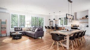 A modern living space with a dining area, a sofa set, and a kitchen. - Nature Escape Near Tremblant: Hot Tub & Lake access (Amherst)