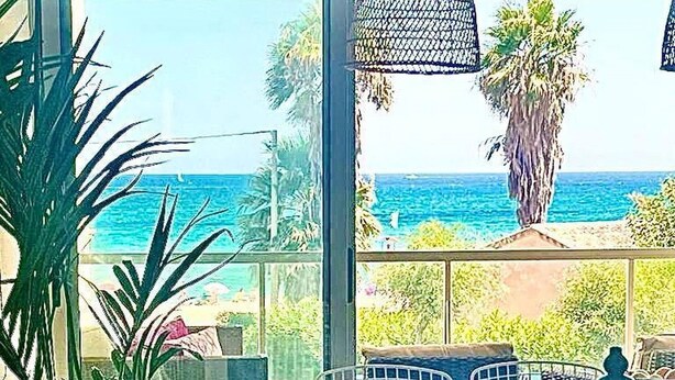 A dining area with a view of the ocean, a large potted plant, and a hanging light fixture. - Tierra de Mar 94 by homeprive (Denia)