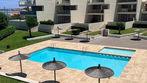 A modern building with a swimming pool, outdoor umbrellas, and a well-maintained garden. - Tierra de Mar 94 by homeprive (Denia)