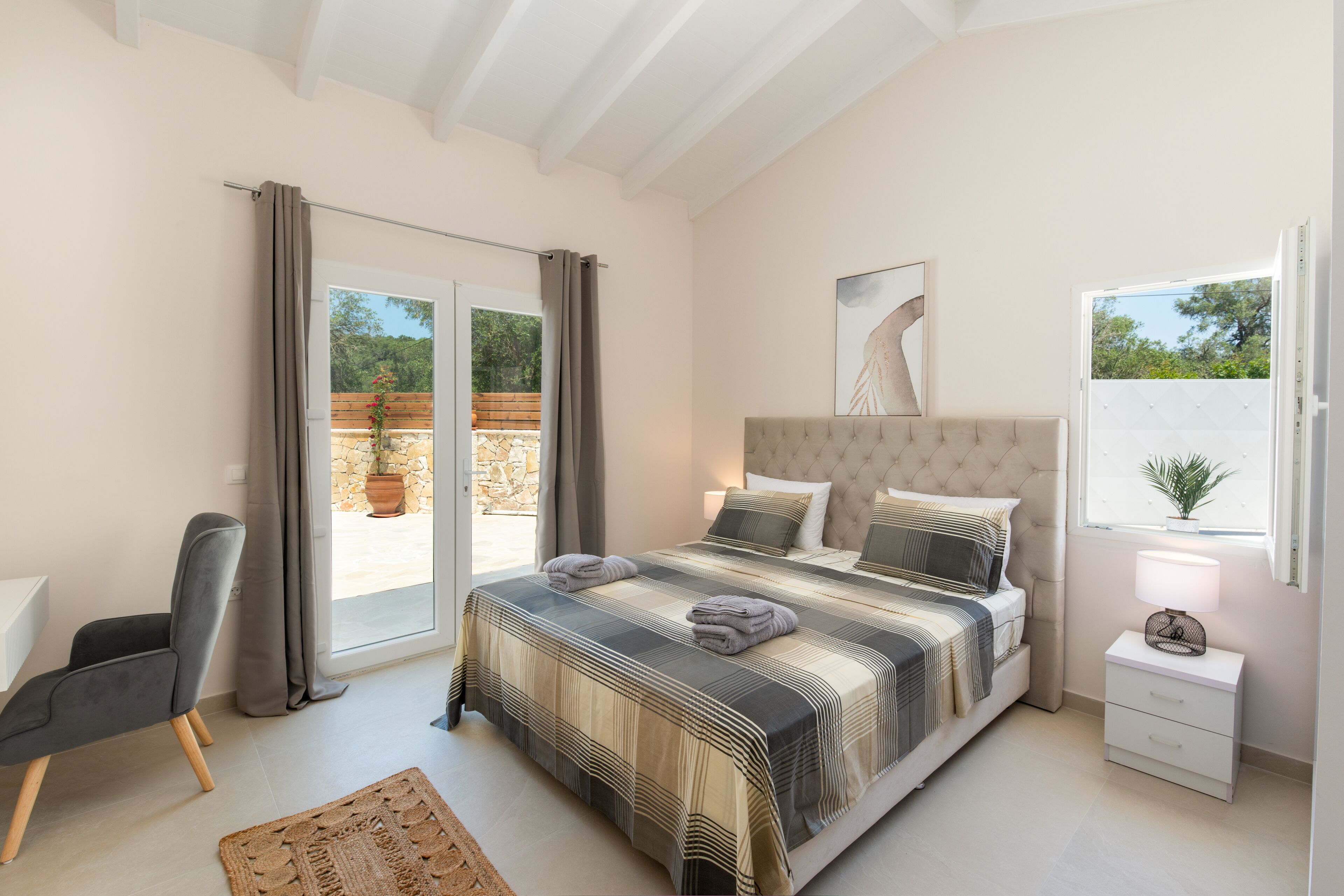 Ein Schlafzimmer mit einem großen Bett, einem Sessel, einem Nachttisch und einem Fenster.