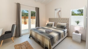 Un dormitorio con una cama grande, una silla, una mesita de noche y una ventana.
