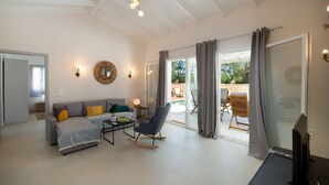Amplia sala de estar con sofá, mecedora, televisor y puerta de vidrio que da a un patio al aire libre.