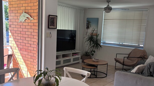 A living room with a TV, a dining table, chairs, a sofa, and a plant. - Centrally Located Coastal Getaway – Walk to Beaches, Cafes & More (Miami)