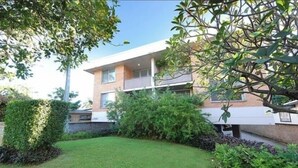 A modern two-story building with a flat roof, large windows, and a balcony on the second floor. - Centrally Located Coastal Getaway – Walk to Beaches, Cafes & More (Miami)