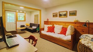Uma sala de estar aconchegante com sofá, cabeceira de madeira e um espaço de jantar com mesa e cadeiras.
