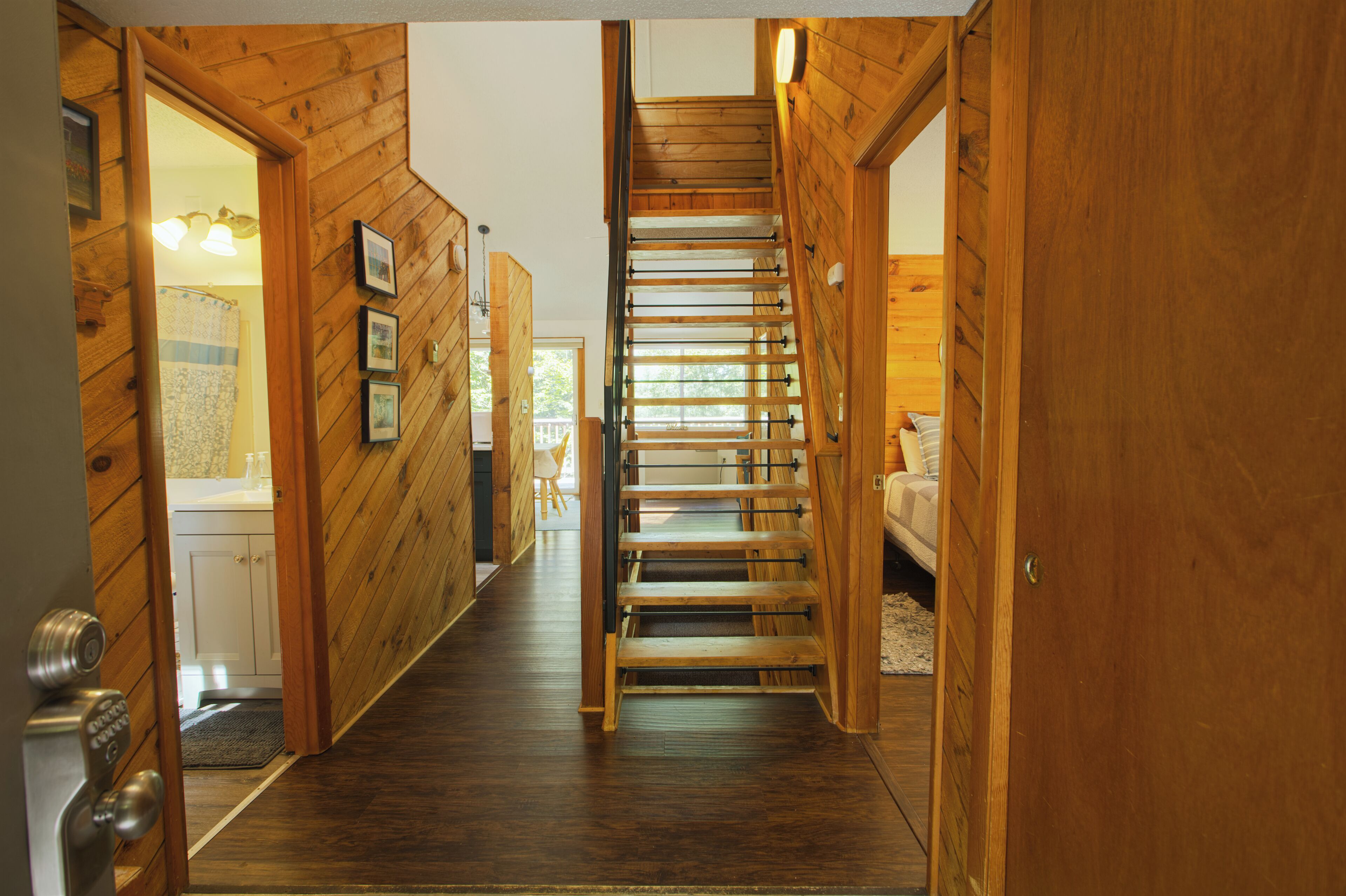 Un pasillo interior de madera con una escalera que sube a un segundo piso.