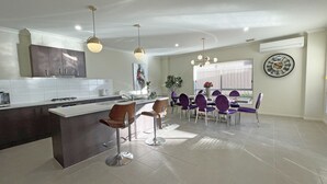 Une cuisine moderne dotée d’un îlot central, de tabourets de bar et de luminaires suspendus.