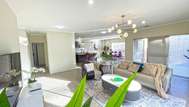 Un salon moderne avec un canapé, une table basse et, au fond, un coin repas.