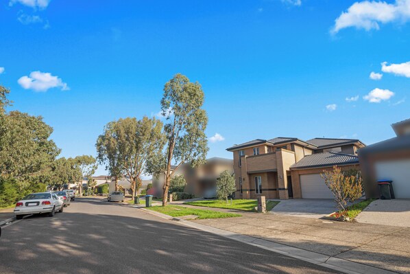 A residential street with houses, parked cars, and a clear blue sky. - Spacious 7BRM 5-bathroom Rental House (Point Cook)