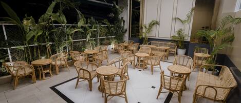 A spacious indoor seating area with wicker furniture and potted plants.