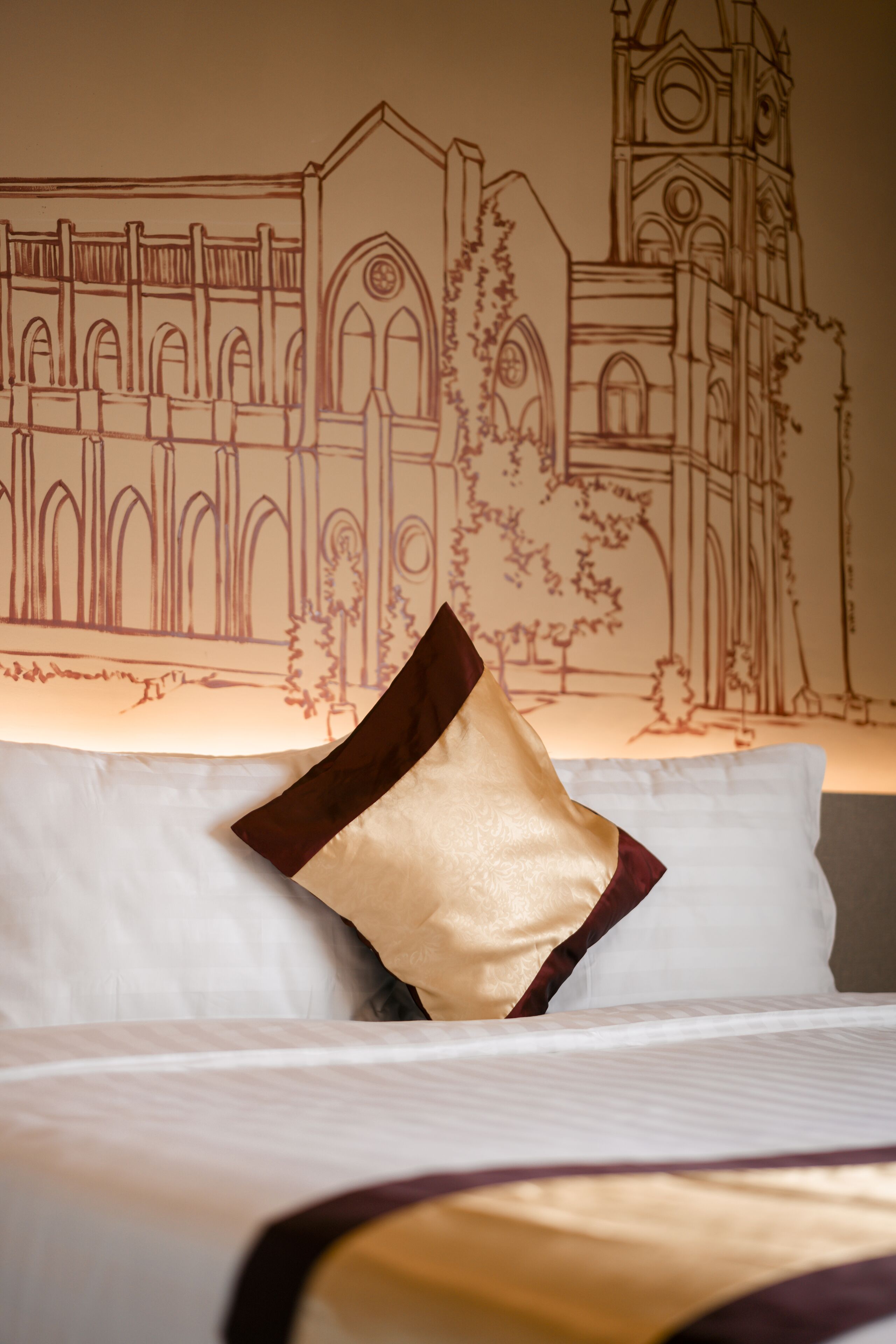 Una cama con sábana blanca y una almohada decorativa.