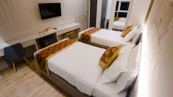 A hotel room with two beds, a desk, a chair, and a TV.