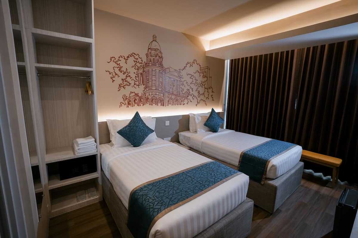 A hotel room with two beds, a wardrobe, a bench, and a wall mural.