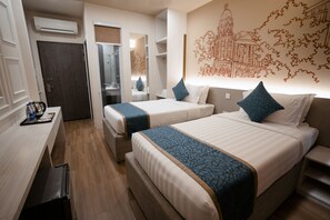 A hotel room with two beds, a desk, and a wardrobe.