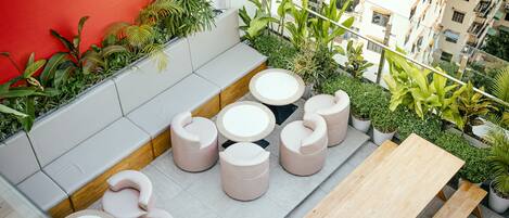 A rooftop terrace with seating areas, potted plants, and a view of the cityscape.
