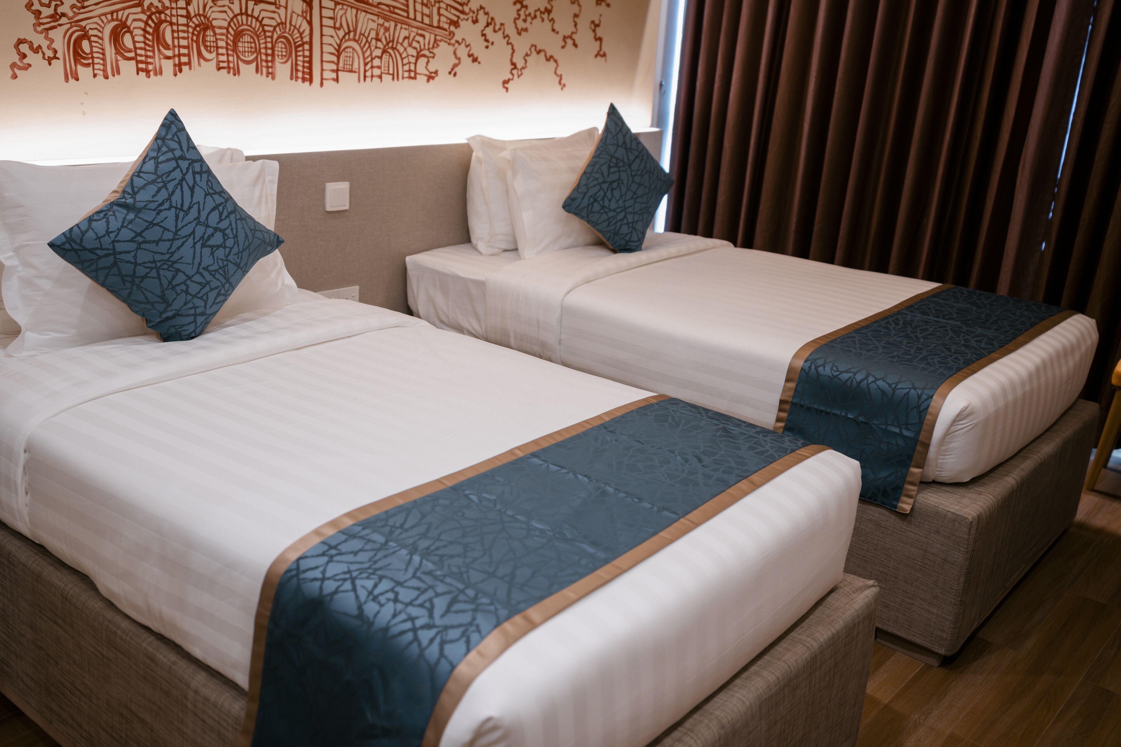 Two single beds with matching headboards and footboards, each with a blue patterned bedspread and pillows.